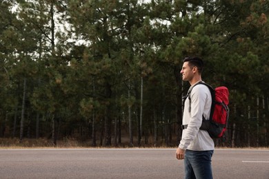 Man with backpack on road near forest