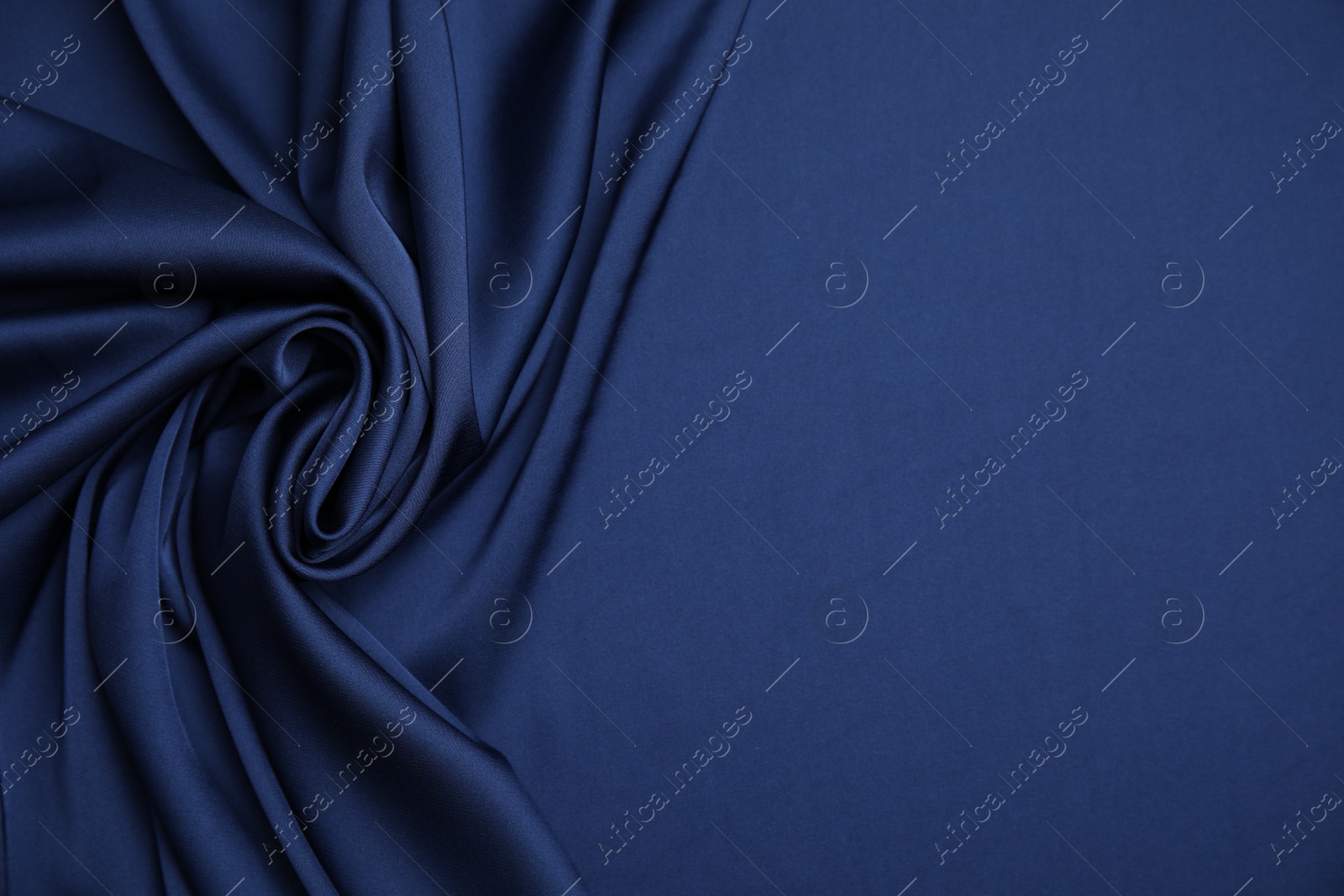 Photo of Crumpled dark blue silk fabric as background, top view. Space for text