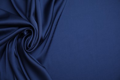 Photo of Crumpled dark blue silk fabric as background, top view. Space for text