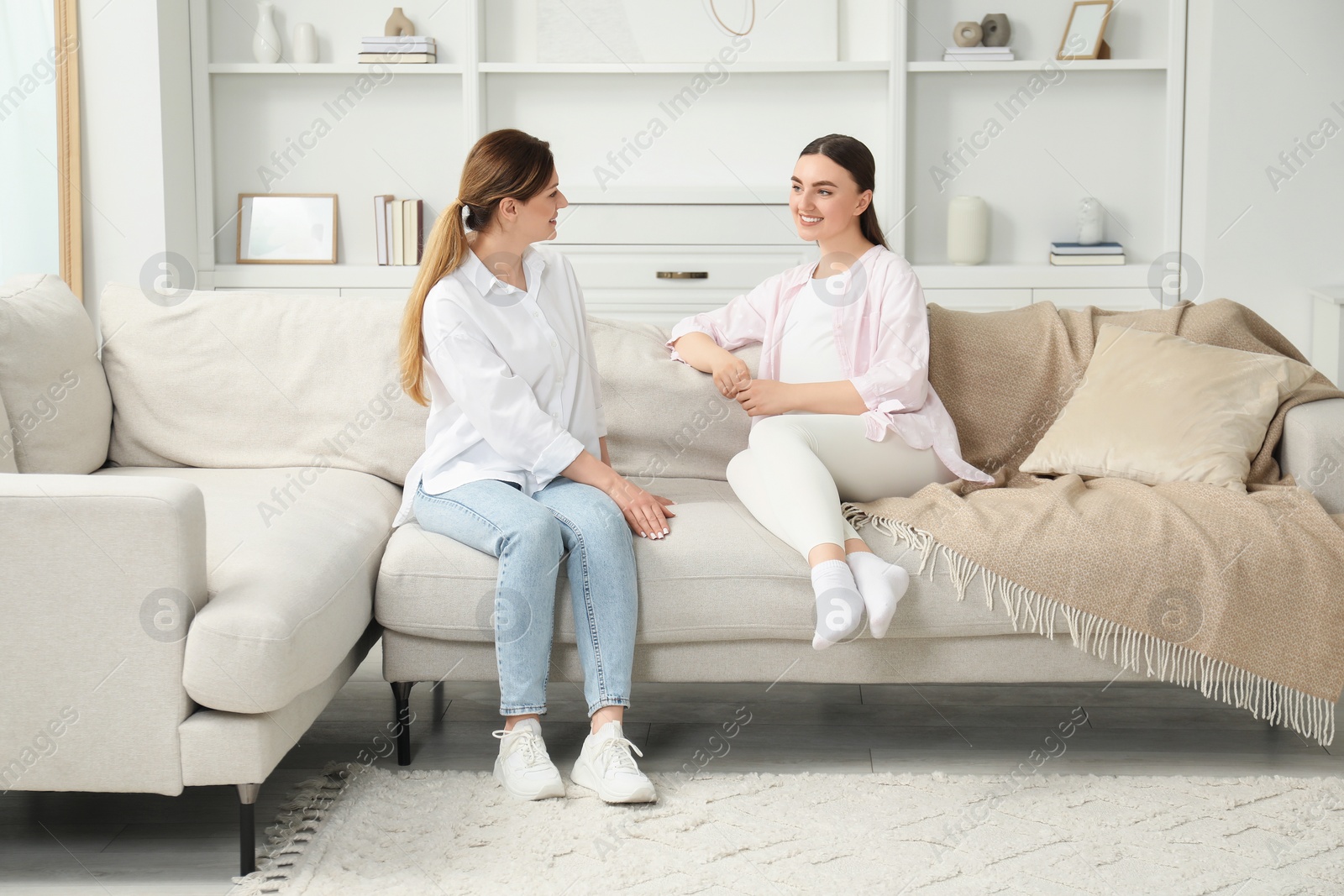 Photo of Doula working with pregnant woman on sofa at home. Preparation for child birth