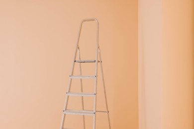 Ladder near pale orange wall. Room renovation