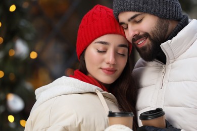 Lovely couple with hot drinks spending time together outdoors