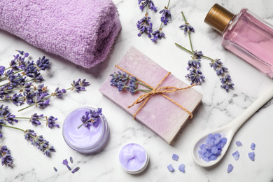 Photo of Cosmetic products and lavender flowers on white marble table, flat lay