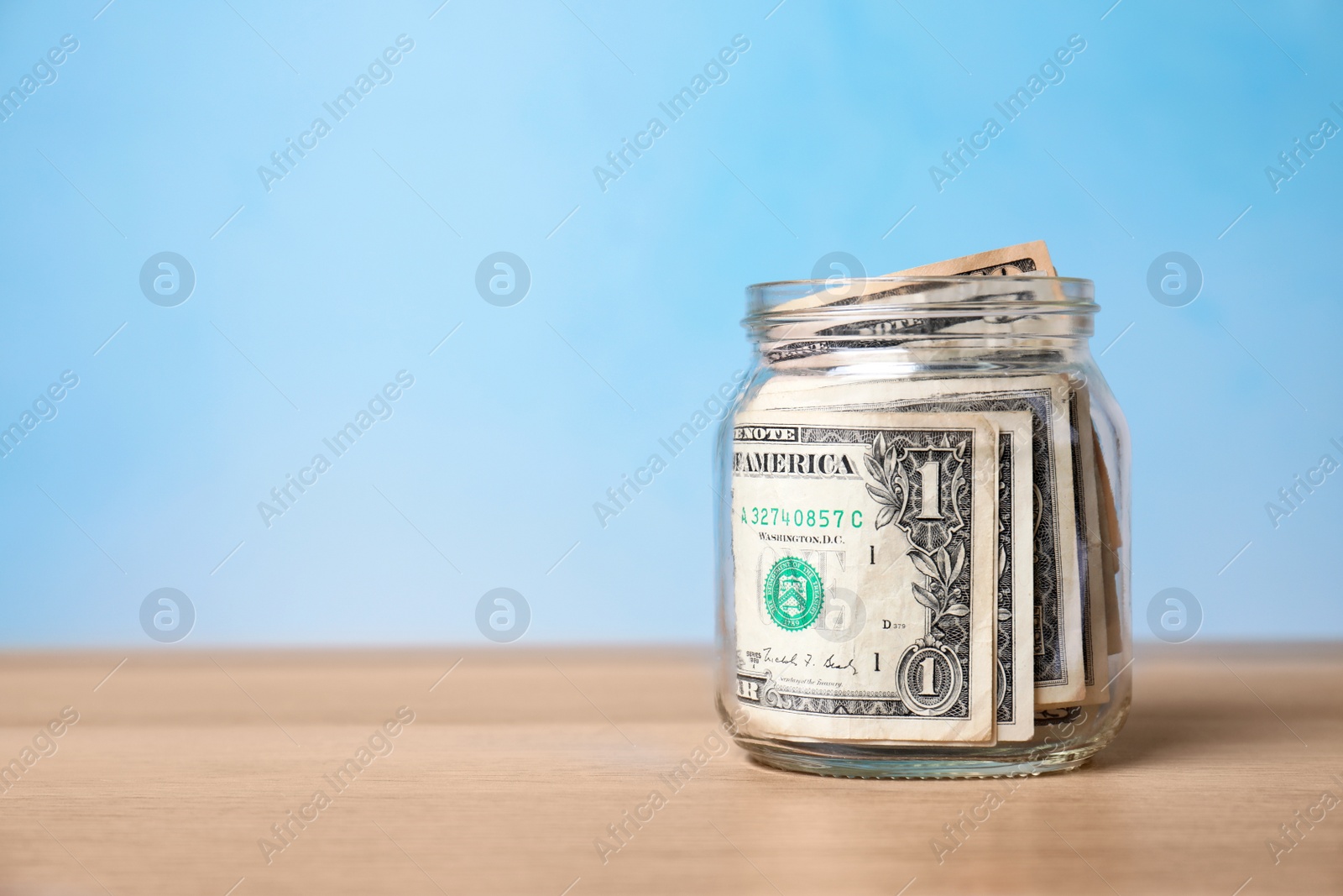 Photo of Donation jar with money on table against color background. Space for text