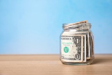 Donation jar with money on table against color background. Space for text