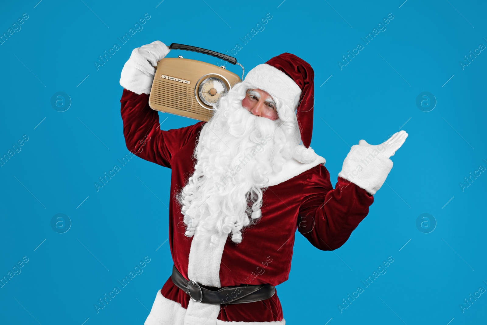 Photo of Santa Claus with vintage radio on blue background. Christmas music