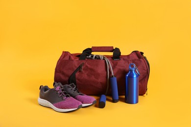 Sports bag and gym equipment on yellow background