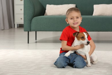 Little boy with his cute dog on floor at home, space for text. Adorable pet