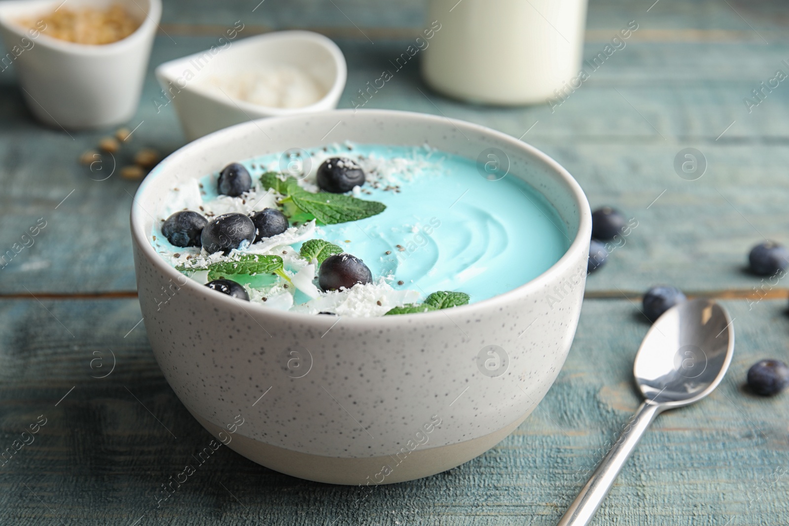 Photo of Bowl of spirulina smoothie and spoon on wooden table