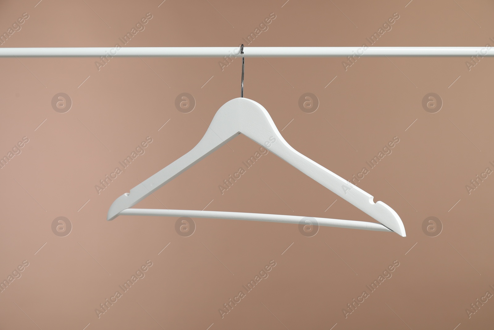 Photo of Empty clothes hanger on rack against light brown background