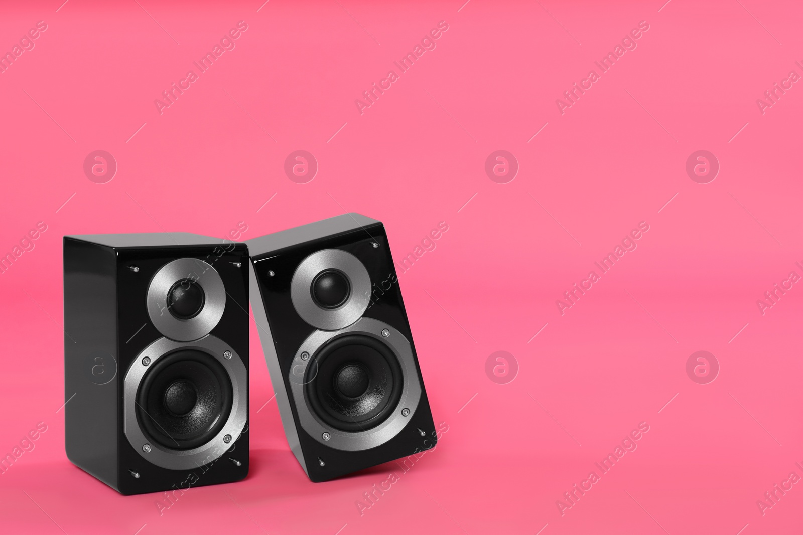 Photo of Modern powerful audio speakers on pink background, space for text