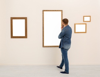 Young man viewing exposition in modern art gallery