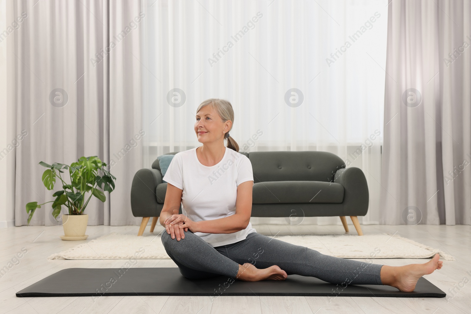 Photo of Senior woman practicing yoga on mat at home