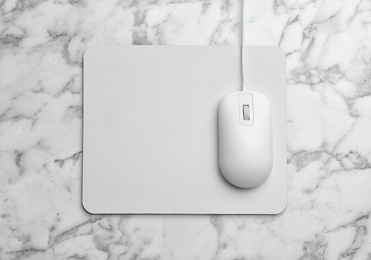 Photo of Wired computer mouse and pad on marble table, flat lay. Space for text
