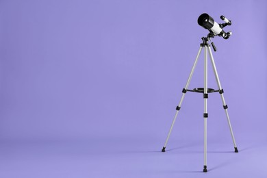 Photo of Tripod with modern telescope on light purple background, space for text