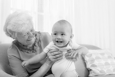 Image of Happy grandmother with little baby at home. Black and white photography