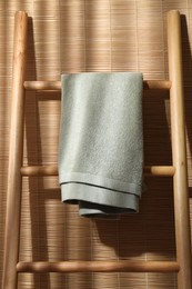 Photo of Green terry towel on wooden ladder indoors