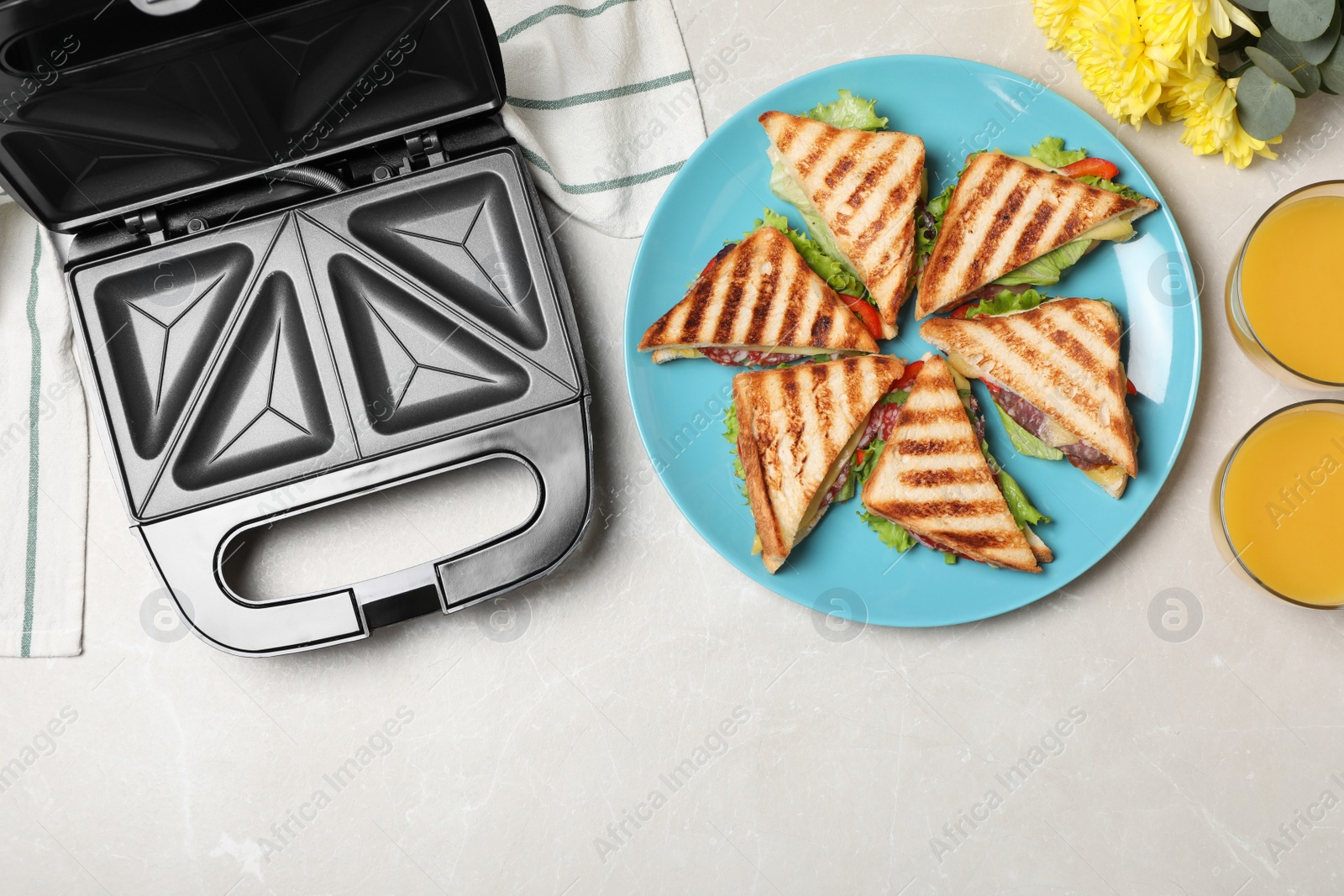 Photo of Modern grill maker and sandwiches on white table, flat lay. Space for text