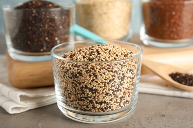 Glass with mixed quinoa seeds on grey table