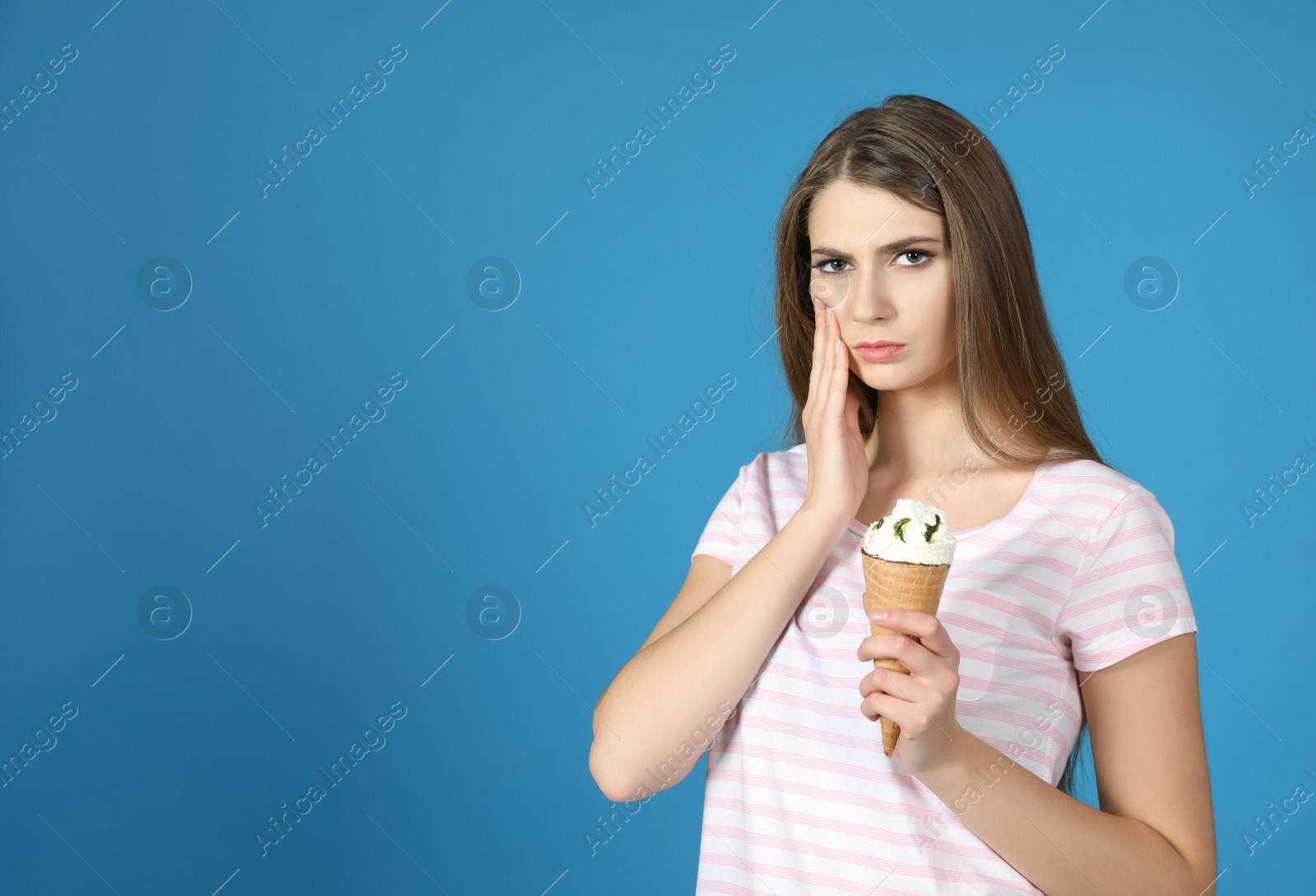 Photo of Emotional young woman with sensitive teeth and ice cream on color background. Space for text