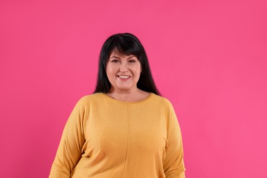 Beautiful overweight mature woman with charming smile on pink background