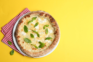 Photo of Delicious cheese pizza with basil on yellow background, top view
