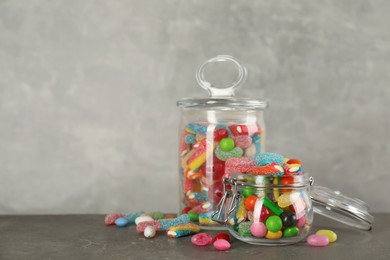 Photo of Jars with different delicious candies on grey table, space for text