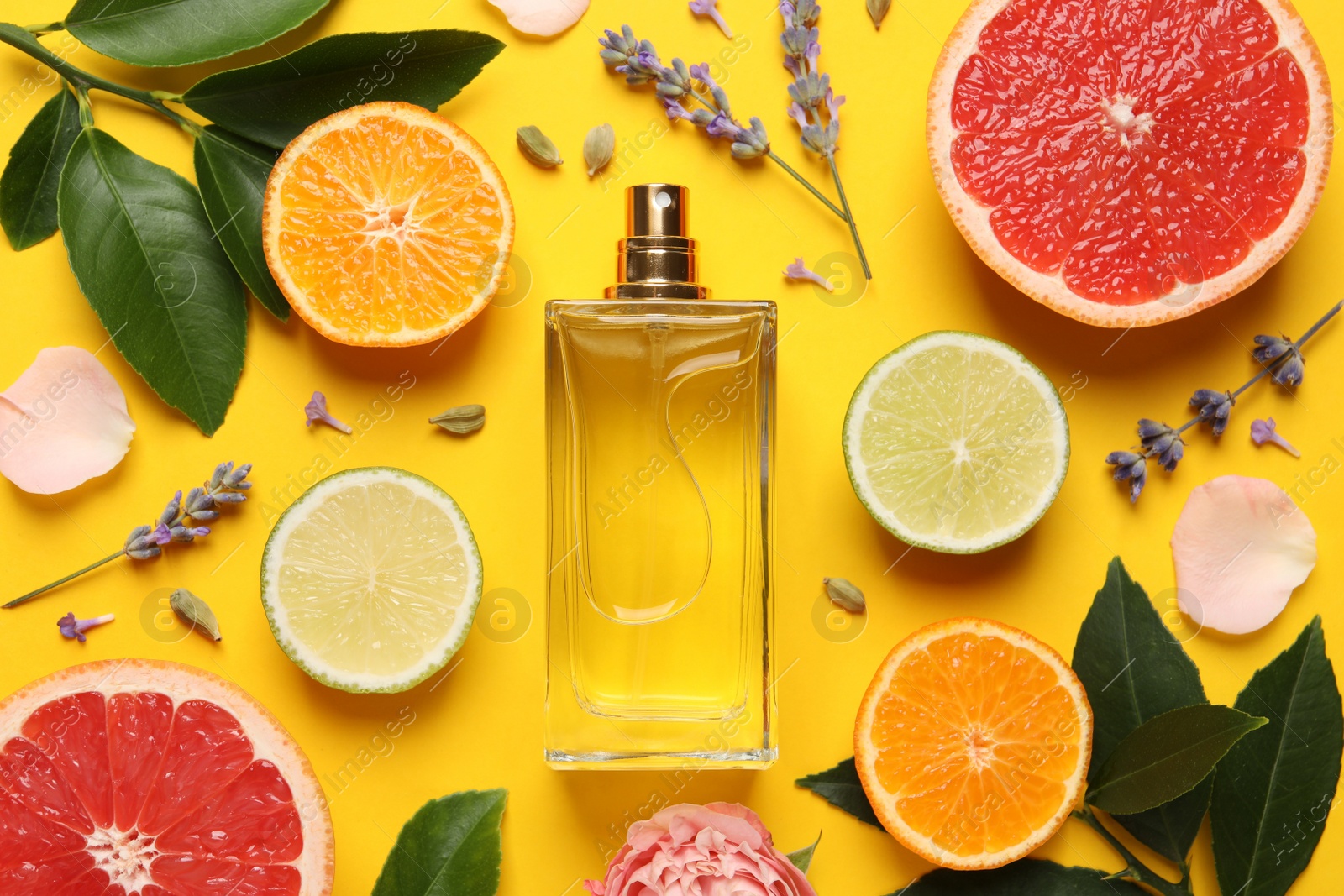 Photo of Flat lay composition with bottle of perfume and fresh citrus fruits on yellow background