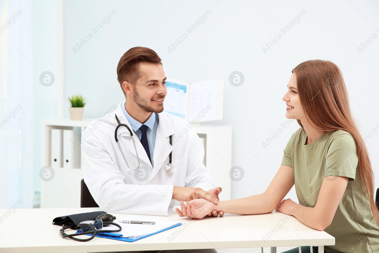 Photo of Doctor checking young woman's pulse in hospital