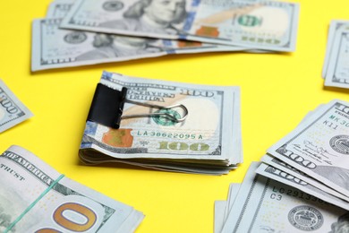 Photo of Dollar banknotes with paper clip on yellow background, closeup