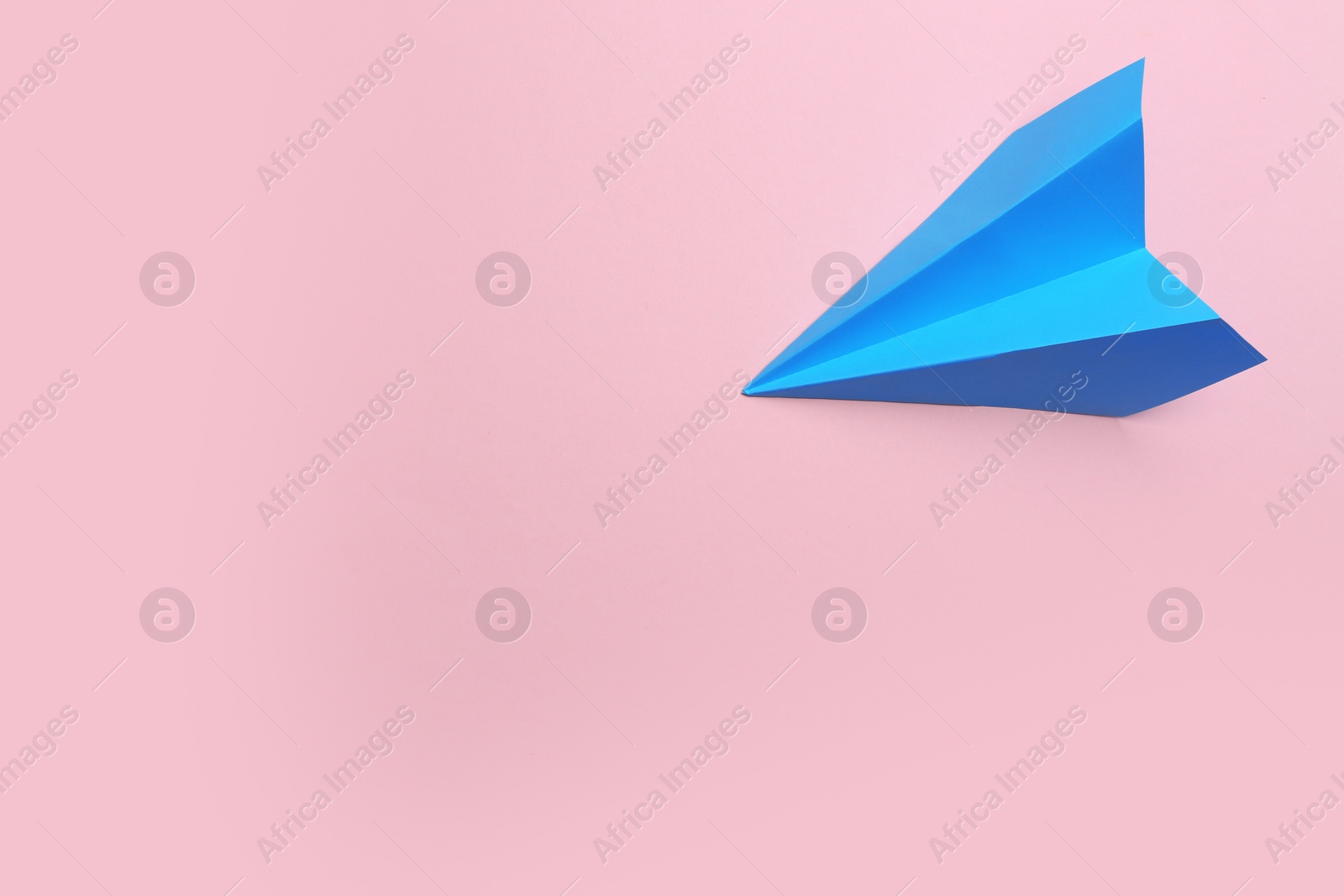 Photo of Light blue paper plane on pink background, top view. Space for text