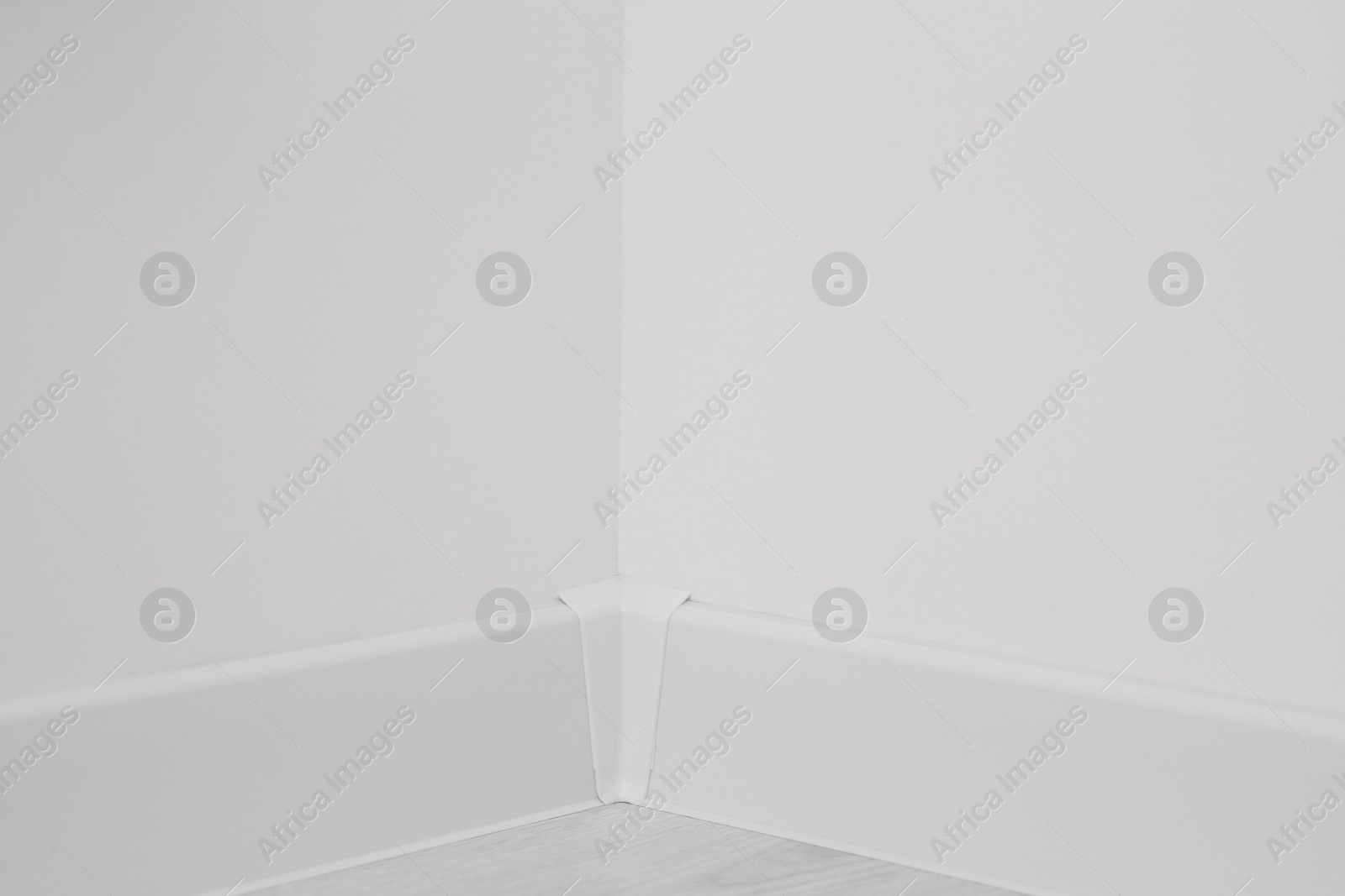 Photo of Corner of white wall with baseboard indoors