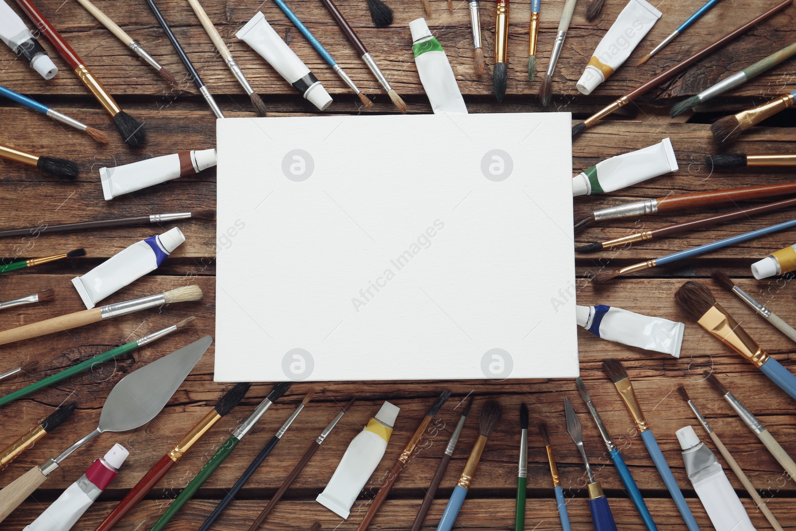 Photo of Blank canvas, brushes and paints on wooden table, flat lay. Space for text