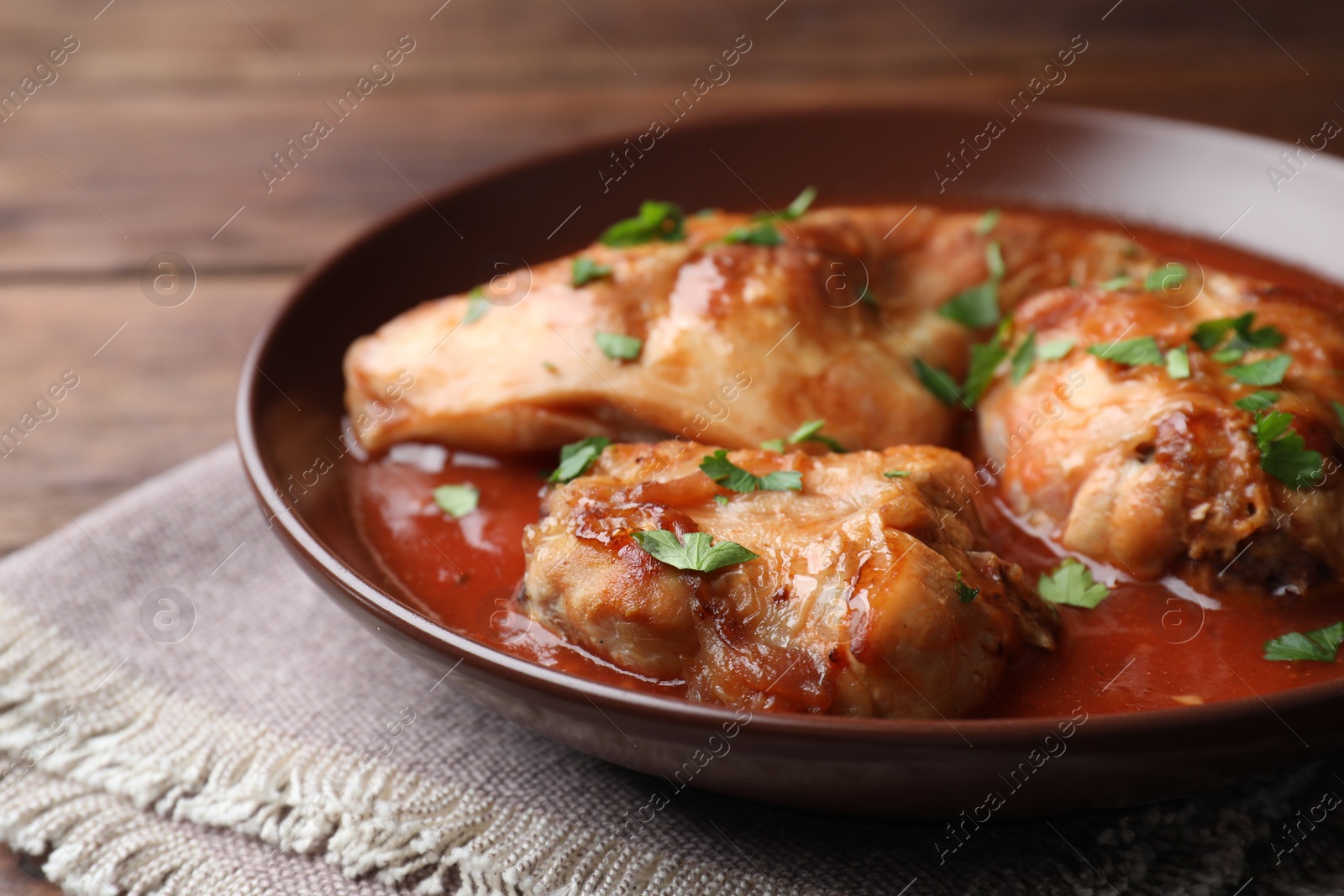 Photo of Tasty cooked rabbit meat with sauce and parsley on table, closeup