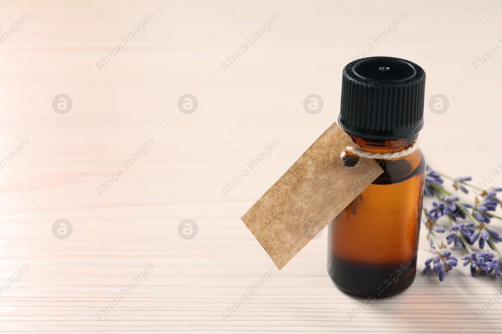 Photo of Bottle of essential oil and lavender flowers on white wooden table, closeup. Space for text