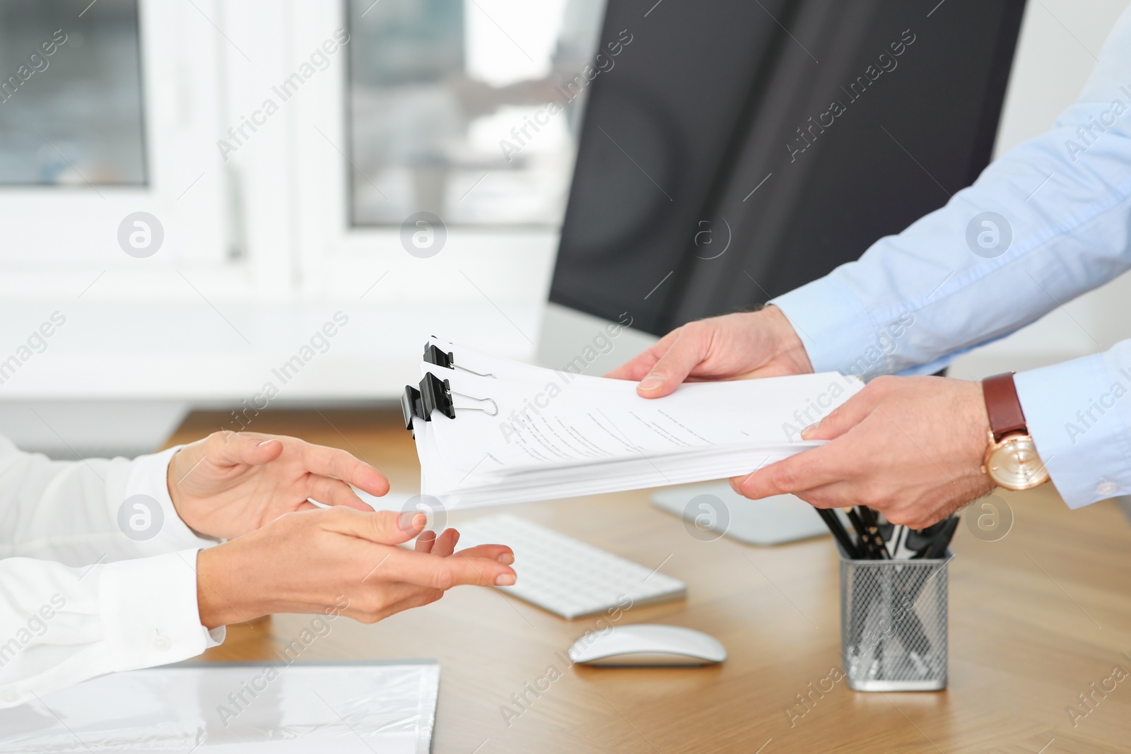 Photo of Man giving documents to colleague in office, closeup