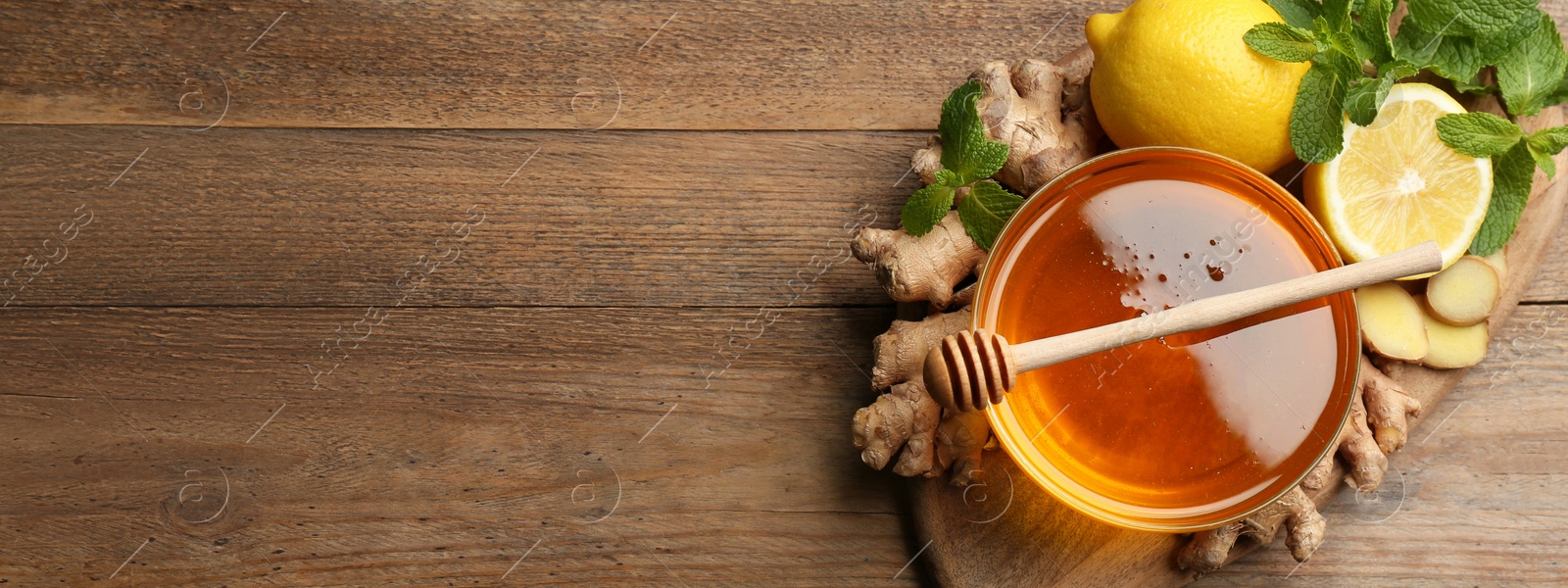 Image of Tasty aromatic honey, lemon, ginger and mint on wooden table, top view with space for text. Banner design