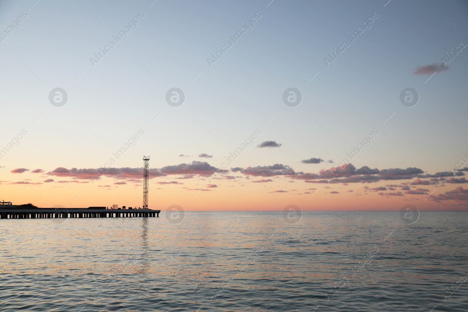 Photo of Picturesque view of pier in sea under beautiful sky at sunset