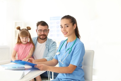 Photo of Little girl with father visiting children's doctor in hospital. Space for text