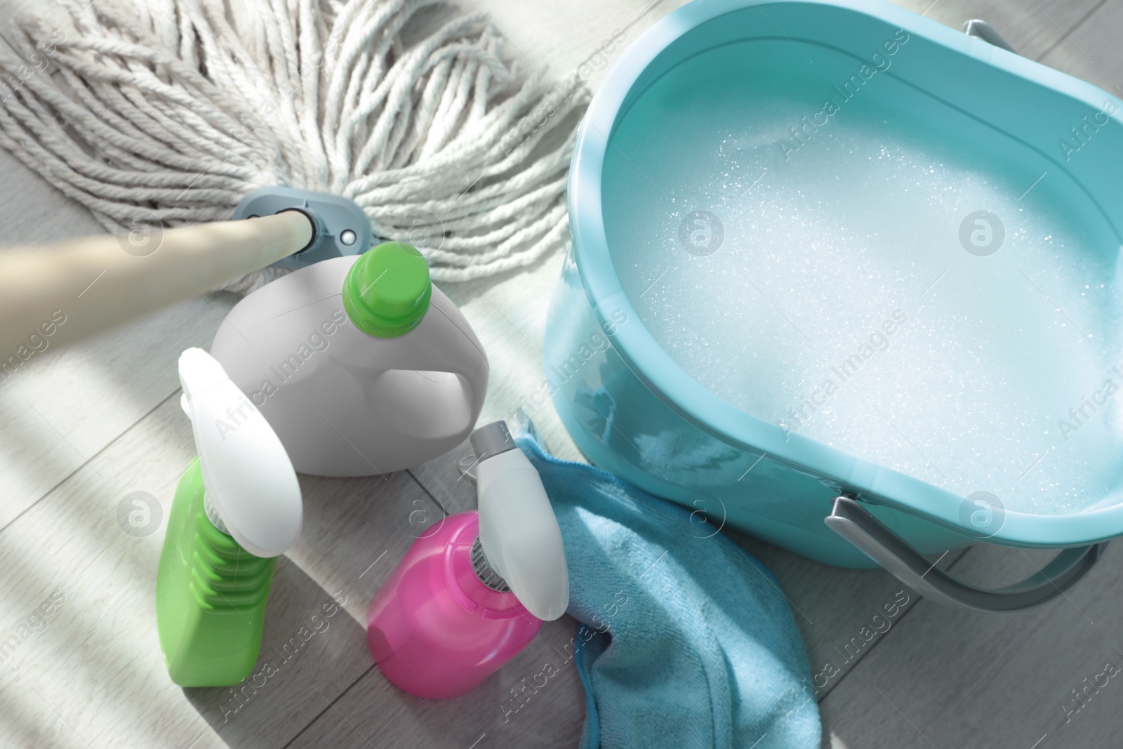 Photo of Bucket, mop and different cleaning supplies on floor, above view