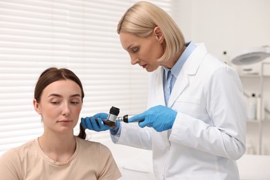 Photo of Trichologist with dermatoscope examining patient`s hair in clinic