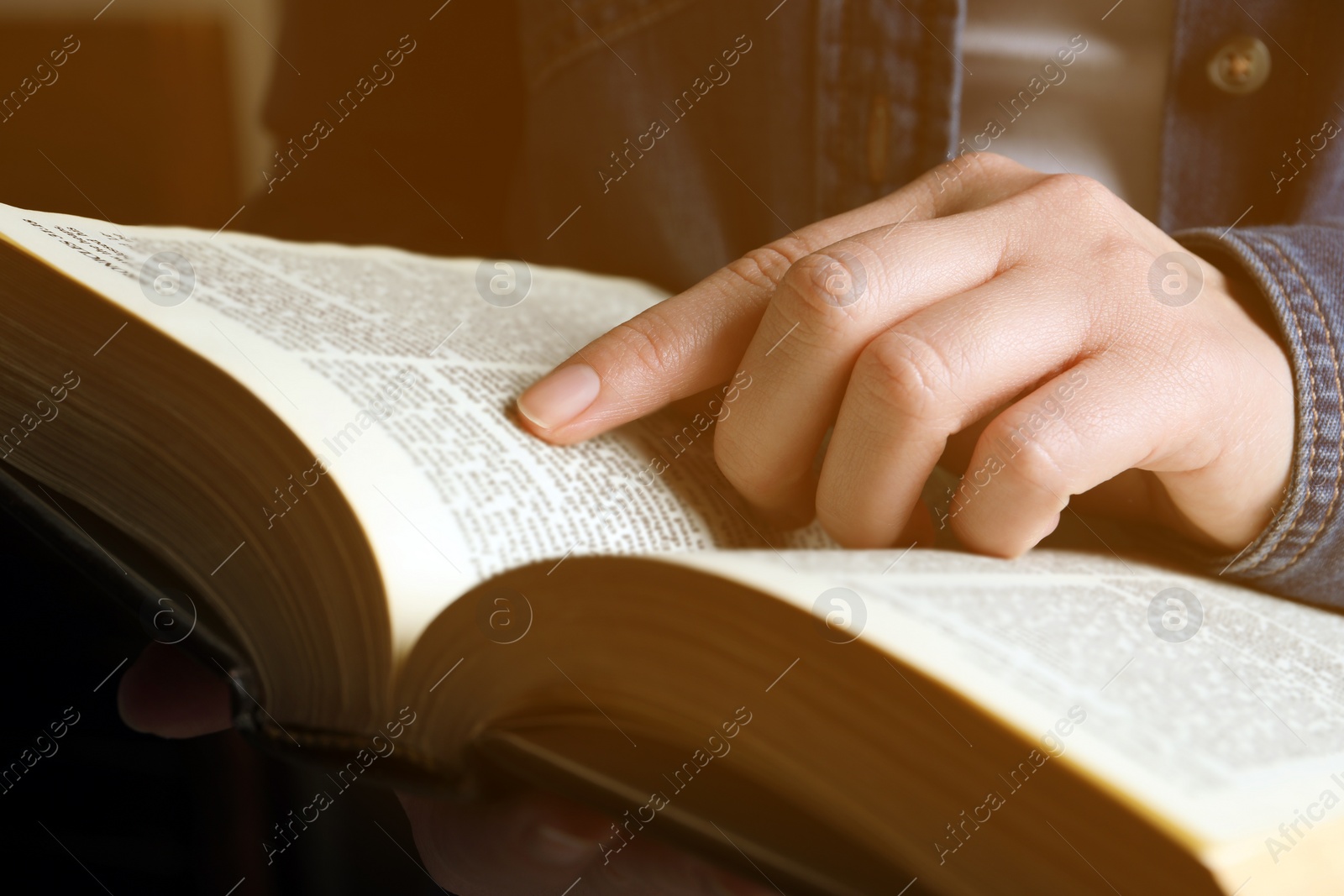 Photo of Woman reading old holy Bible on blurred background, closeup