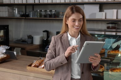 Photo of Happy business owner with tablet in bakery shop. Space for text