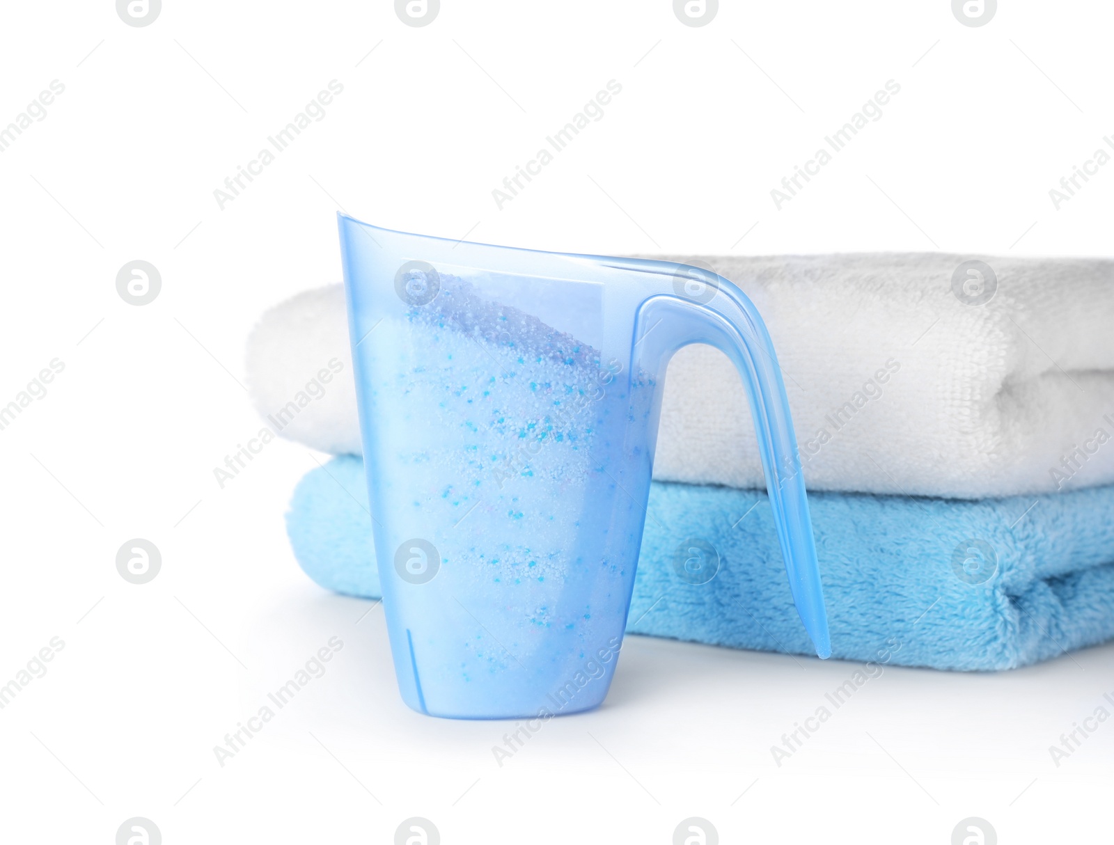 Photo of Laundry detergent in plastic measuring cup and towels on white background