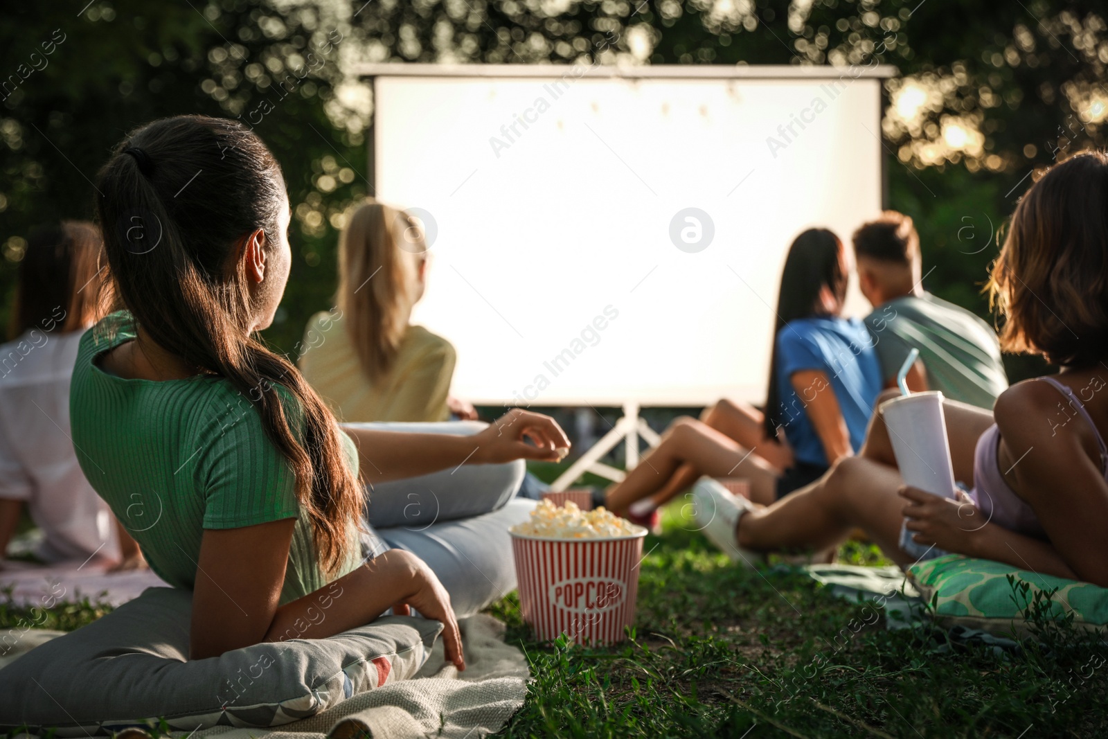 Photo of Young people with popcorn watching movie in open air cinema. Space for text