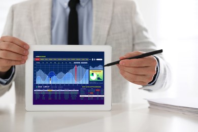 Image of Man analyzing electronic trading platform on tablet indoors, closeup. Stock exchange