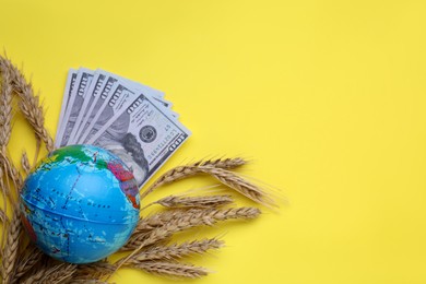 Photo of Import and export concept. Globe, ears of wheat and money on yellow background, flat lay with space for text
