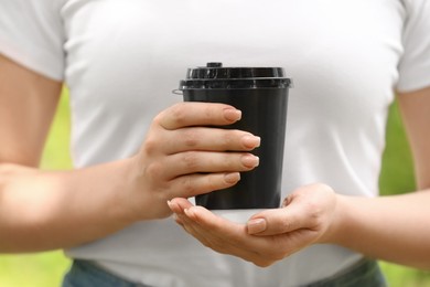 Woman with takeaway coffee cup in park, closeup