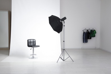 Photo studio interior with modern chair and professional lighting equipment