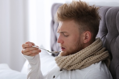 Sick young man eating soup to cure flu in bed at home